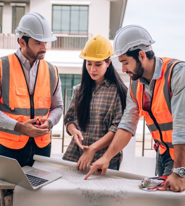 Civil engineer , Construction worker and Architects wearing hardhats and safety vests are working together at construction site ,building ,home in cooperation teamwork concept.
